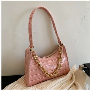 Detail shot of pink crocodile pattern leather underarm bag with decorative gold chunky chain