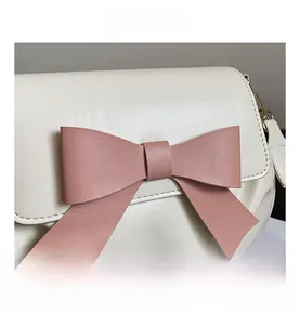 Détail d'un sac en cuir blanc crème avec un nœud rose et des ferrures dorées