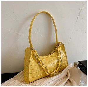 Detail of vivid yellow faux crocodile skin texture and amber chain strap on bag