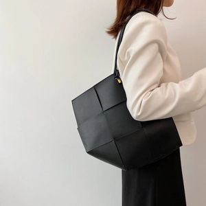 Large black woven leather tote bag shown with an elegant white blazer outfit