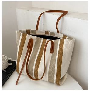 Detail of striped canvas tote bag showing textured fabric and brown leather straps