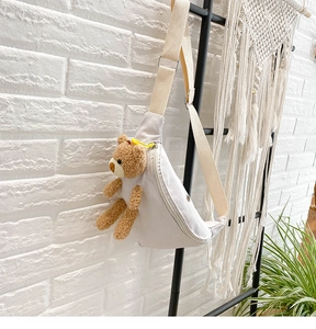 Detailed view of cream canvas chest bag featuring a cute plush bear and metal zipper