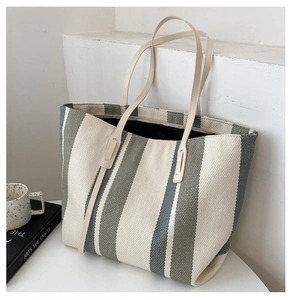 Detail of spacious striped canvas tote bag with long beige leather handles for daily use