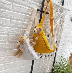 Detail of canvas chest bags in yellow and white featuring 3D plush teddy bear ornaments