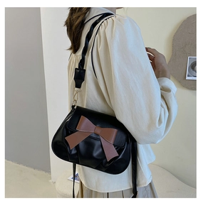 Détail du sac bandoulière noir avec nœud marron et bandoulière torsadée porté