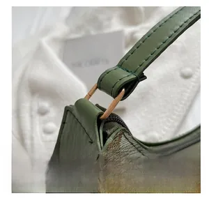 Close-up of bronze hardware D-ring connector and green leather strap on floral handbag