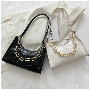 Detailed close-up of crocodile texture and chunky chain strap on black and white shoulder bags