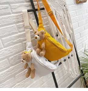 Detail of canvas chest bags with plush bear decor and adjustable straps on display