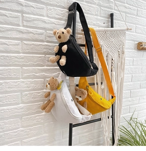 Three canvas cross-body bags with teddy bear plush in black, white, and yellow colors