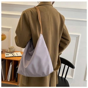 Détail d'un sac à épaule en nylon lavande porté avec un manteau en laine marron