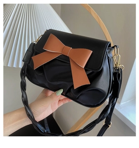 Détail du sac bandoulière plissé noir avec grand nœud marron et bandoulière tissée