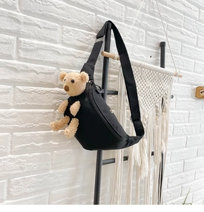 Detail of black canvas chest bag featuring a 3D plush bear and adjustable strap
