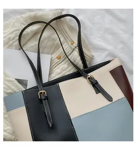 Flat lay of a multicolor patchwork PU leather tote bag with adjustable gold buckles