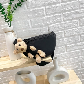 Detail of black canvas waist bag featuring a 3D plush teddy bear and zipper closure