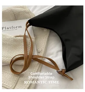 Détail des fines bandoulières en cuir synthétique marron sur un sac en nylon noir