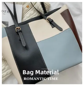 Detailed view of color-block tote bag with white stitching and decorative gold buckles