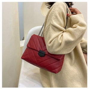 Detail of burgundy chevron quilted bag with matte black clasp and chain strap