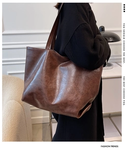 Gros plan sur la texture cuir vintage marron et la large bandoulière du sac cabas