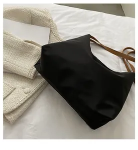 Gros plan sur le fond renforcé et la structure spacieuse du sac à épaule en nylon noir