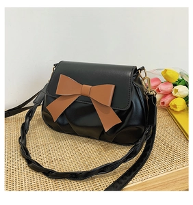 Détail du sac bandoulière noir avec nœud marron et bandoulière tissée élégante
