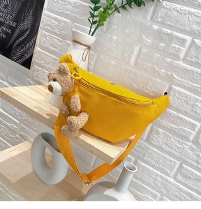 Detailed view of yellow canvas waist bag featuring a 3D plush teddy bear and adjustable strap