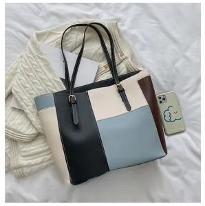 Close-up of color-blocked PU leather tote bag showing large capacity for smartphone