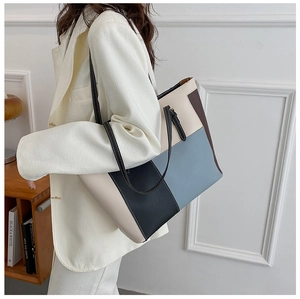 Detail of color-block PU leather tote bag featuring modern blue, black and cream panels