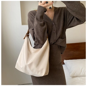 Détail du sac hobo en nylon crème avec bandoulière en cuir marron porté par un mannequin