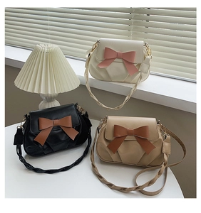 Trois sacs bandoulière plissés avec grands nœuds et bretelles tressées dans un salon chic