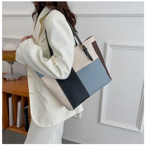 Detail of color-blocked tote bag with adjustable gold buckle on black shoulder strap