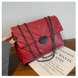 Detail of red quilted faux leather bag with V-shaped stitching and black chain strap