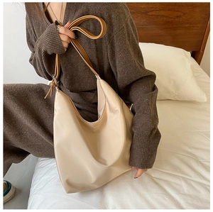 Vue détaillée d'un sac hobo beige souple avec bandoulière en cuir dans un décor de chambre