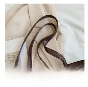 Détail de la poignée large renforcée et du cuir marron foncé brillant du sac cabas