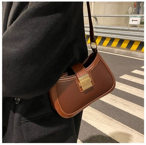 Detail of vintage brown leather underarm bag featuring a large square golden buckle closure