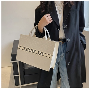Détail du sac cabas en toile avec motifs de lettres et texte mode porté par un mannequin