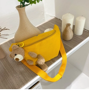 Detail of yellow canvas chest bag featuring a cute 3D teddy bear with adjustable strap
