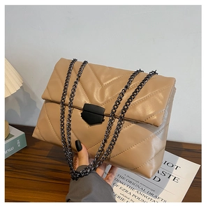 Detail of beige quilted shoulder bag with V-shaped stitching and black metal chain strap