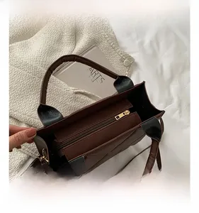 Detail view of brown quilted tote bag showing smooth gold zipper and black handle