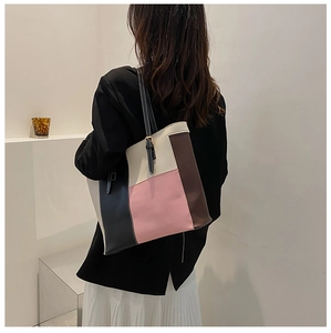 Detail of color-block PU leather tote bag showing pink, black, and beige patchwork texture