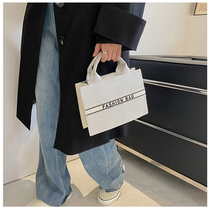 Détail du sac cabas blanc avec motif M gaufré et sangle mode noire et blanche