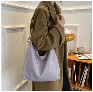 Sac à épaule en nylon violet chic porté avec un manteau d'hiver marron élégant