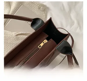 Detail of dark brown embossed leather bag featuring a smooth gold metal zipper