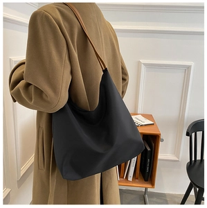 Détail du sac hobo en tissu Oxford noir avec une fine bandoulière marron