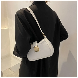 Close-up of minimalist white half-moon underarm bag with gold metal buckle on shoulder