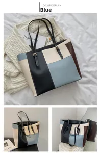 Detail view of large color-block tote bag in blue, black, and beige with gold buckles