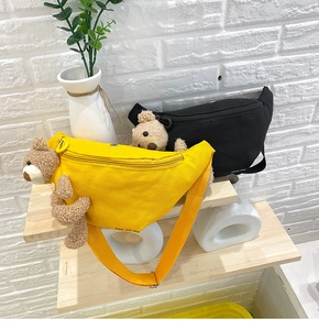 Detail of canvas chest bags in yellow and black featuring cute plush bear accessories