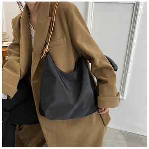 Détail du sac hobo en tissu oxford noir avec bandoulière en cuir porté par un mannequin