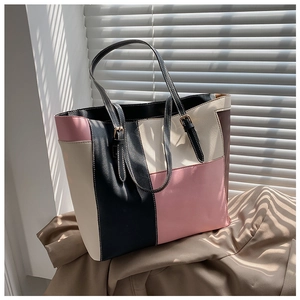 Detail of color-block tote bag with adjustable straps and golden buckles in natural light