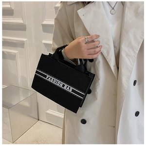 Sac fourre-tout en toile noire avec sangle blanche et texte sur manteau beige