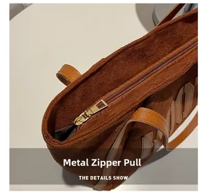 Detailed macro view of the golden metal zipper pull and premium suede fabric on the tote bag